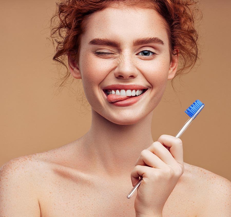 Redhead female holding toothbrush and making a silly face