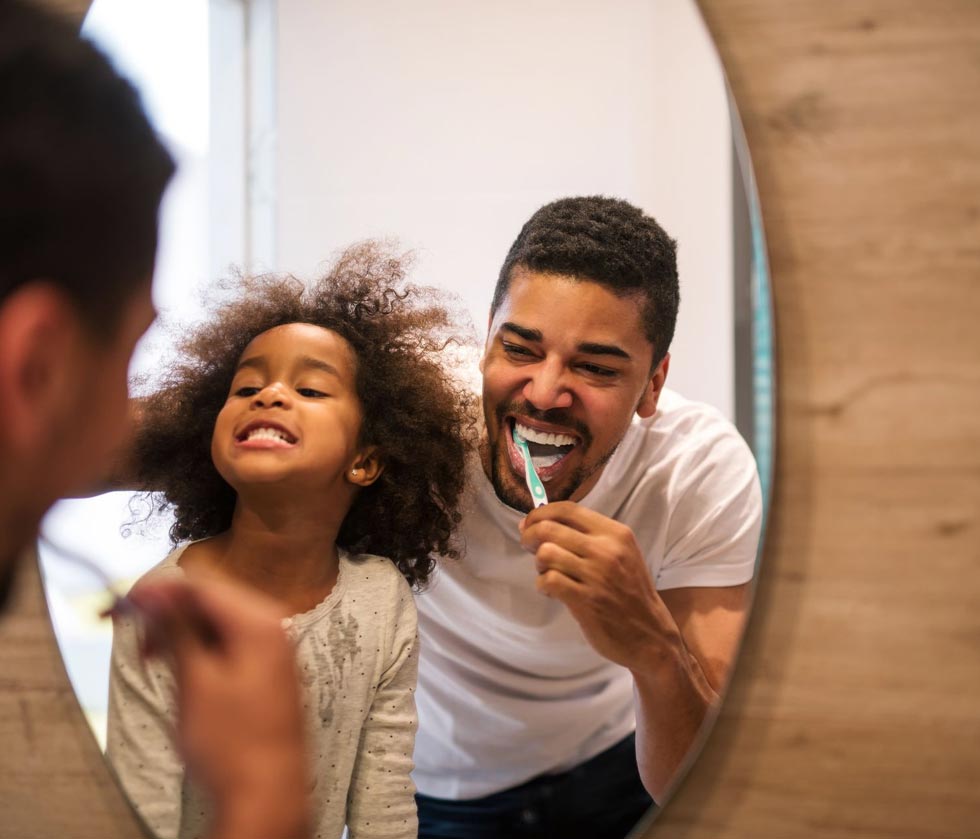 Father and daughter brushing their teeth